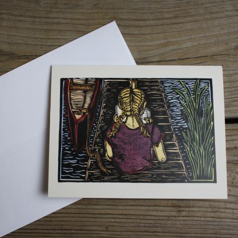 Card showing girl reading on a dock, with envelope