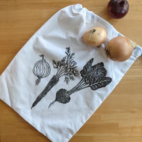 drawstring bag printed with root vegetables; arranged with some onions