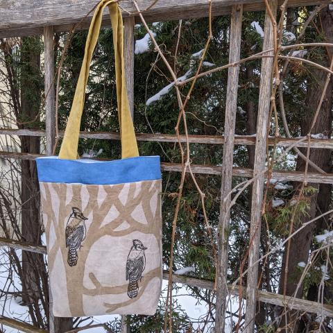 PLant dyed canvas tote bag, with two bluejays sitting in the trees pictured on the side