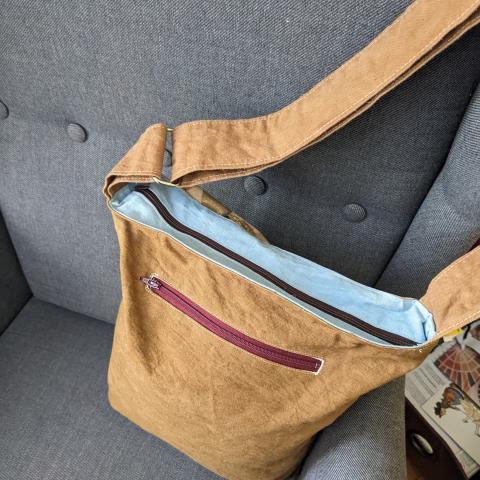 top zipper closure of canvas bag with a leafy pattern and an adjustable shoulder strap