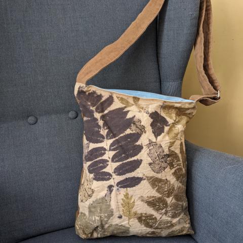 canvas bag with a leafy pattern and an adjustable shoulder strap
