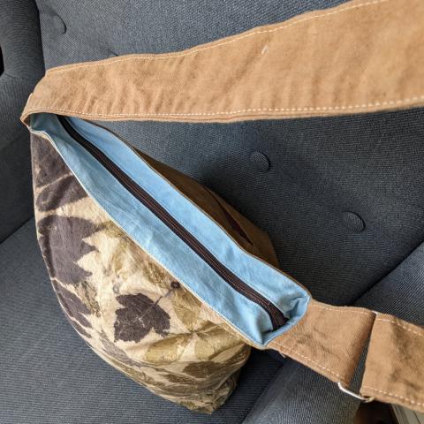 top zipper closure of canvas bag with a leafy pattern and an adjustable shoulder strap