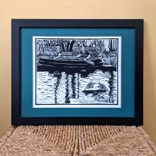 Framed Linocut print of two people in a canoe and two turtles in the foreground