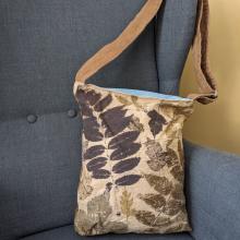 canvas bag with a leafy pattern and an adjustable shoulder strap